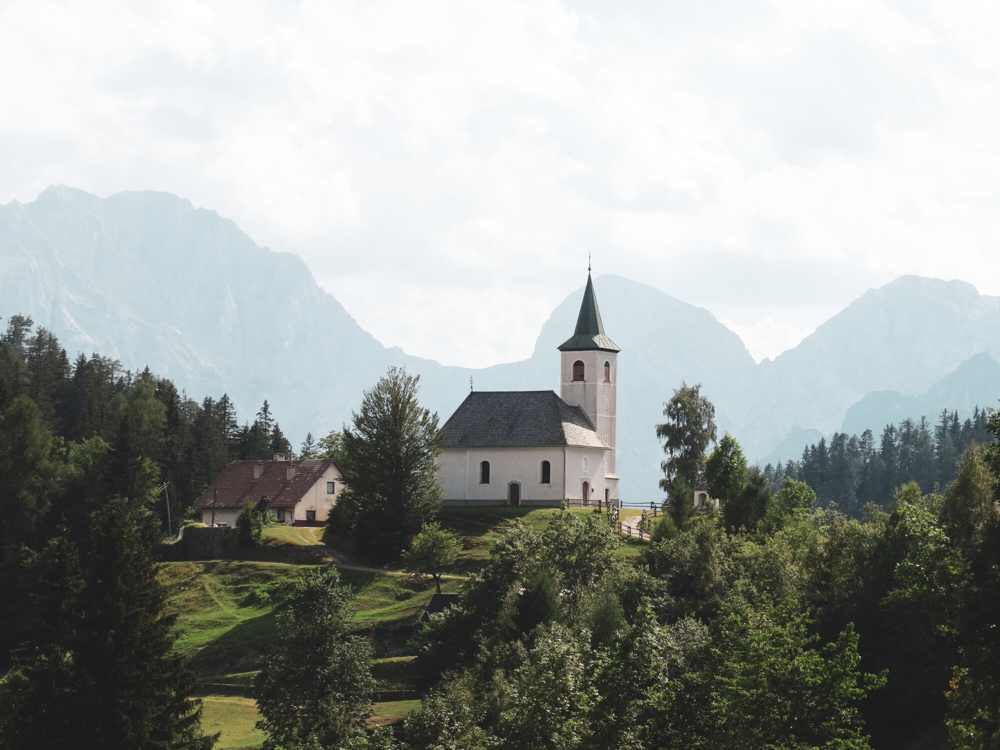 Une jolie église blanche au toit vert vue depuis la route panoramique Solcava, Slovénie
